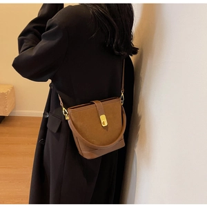 Close-up of brown vintage bucket bag featuring suede texture and gold metal buckle