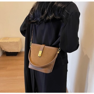Brown bucket bag detail showing matte and smooth leather texture with gold square buckle