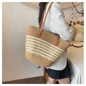 Detail of the large straw tote bag featuring woven stripes and slim leather straps