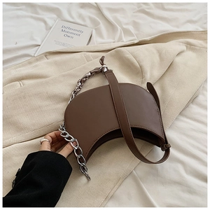 Détail d'un sac demi-lune marron avec chaîne argentée et texture en similicuir lisse