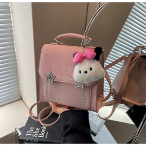 Close-up of pink crossbody bag with star clasp, pearl trim and plush puppy charm