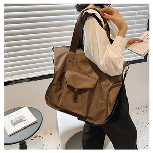 Detail of dark brown waterproof nylon tote bag with decorative resin chain on large pocket
