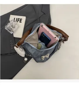 Top view of large denim tote bag showing spacious grey fabric interior and metal bow detail
