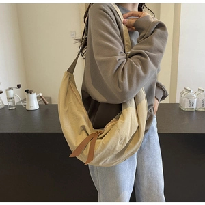 Detail of a khaki nylon crescent bag with wide strap and premium leather zipper pull