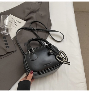 Detail of black mini bowling bag featuring contrast white stitching and heart charm