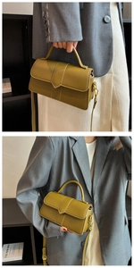 Olive green rectangular crossbody bag with top handle shown held by model in casual wear