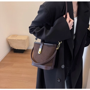 Detail of vintage coffee brown suede bucket bag featuring a bright gold metal buckle