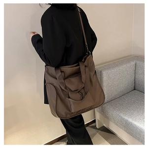Waterproof nylon tote bag with adjustable shoulder straps shown in casual street style