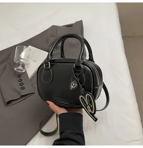 Close-up of black leather bowling bag with white stitching and heart-shaped pendant