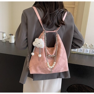 Close-up of pink quilted suede backpack with bow, pearl charms and a cloud pendant