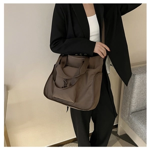 Detail of a dark brown nylon tote bag with functional pockets and versatile carrying straps