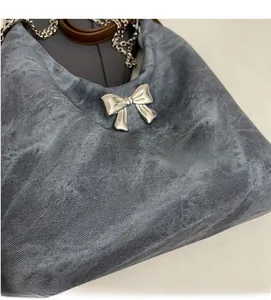 Detailed view of dark grey washed fabric texture and silver metal bow on crossbody bag