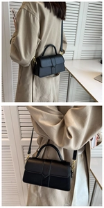 Detail of a black leather crossbody bag featuring gold hardware and a curved top handle
