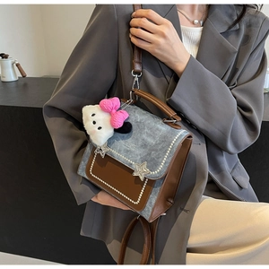 Detail of a contrast leather and denim handbag with pearl trim and star accents