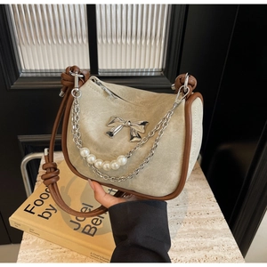 Detail of suede handbag with pearl metal chain and metallic bow ornament
