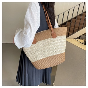 Detail of large woven straw tote bag with brown leather handles and tricolor design