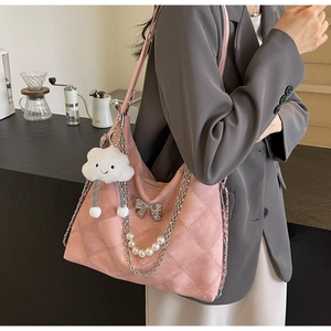Detailed shot of pink quilted tote with pearl chain, metal bow and cloud pendant