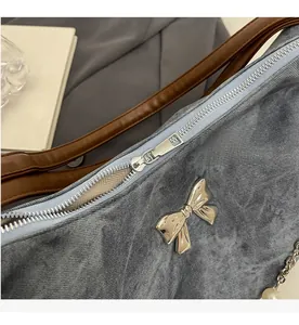 Detailed macro view of smooth silver zipper and bow buckle on grey washed shoulder bag