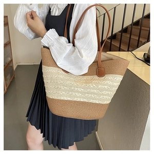 Detail of handwoven straw tote bag with striped pattern and premium leather shoulder straps
