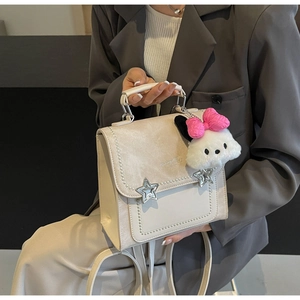 Detail of retro cream leather bag with pearl trim, star buckles and plush puppy charm