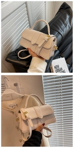 Detail of a beige textured crossbody bag with golden hardware and adjustable strap