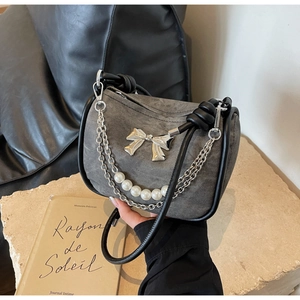 Close-up of gray denim handbag featuring silver metal bow and elegant pearl chain strap