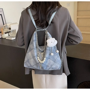Detail of light blue denim tote with metal chain, pearls and cloud plush charm decoration