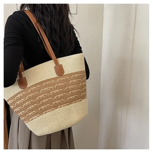 Detail of color-block straw tote bag with brown leather straps shown on a model