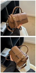 Close-up of brown leather crossbody bag with vertical stitching and gold hardware
