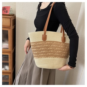 Detail of hand-woven large straw tote bag with brown leather shoulder straps for beach trips