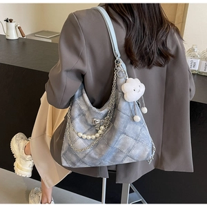 Close-up of quilted light blue denim tote bag with pearl chain and cloud pendant detail