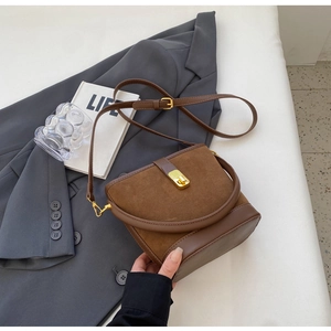 Detail view of brown vintage suede bucket bag with gold clasp on textured background