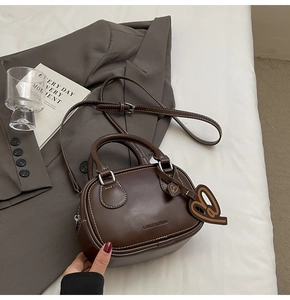 Detail view of dark brown bowling bag with white stitching and leather heart charm
