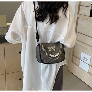 Chic grey shoulder bag with pearl chain and silver bow detail on a white shirt model