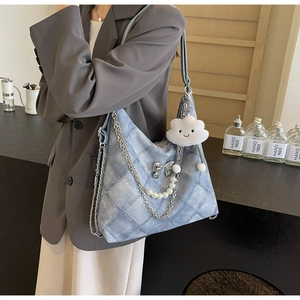 Detail of light blue quilted shoulder bag with silver bow charm and pearl chain decoration