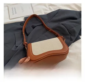 Close-up of a brown and beige patchwork underarm bag on a suit and white sheets