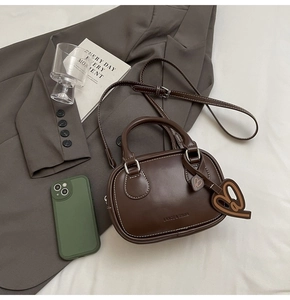 Detail of coffee brown mini bowling bag with silver hardware and heart charm