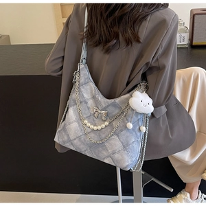 Close-up of denim tote bag featuring pearl chains, silver bow and cloud plush charm