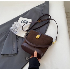Detail of coffee brown bucket bag with suede leather textures and golden metal clasp