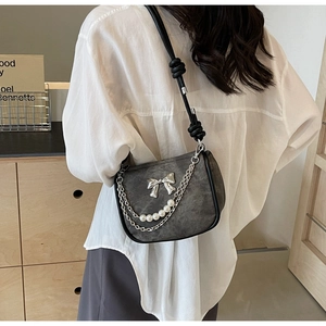 Detailed view of charcoal grey bag with silver metal bow and decorative pearl chain strap