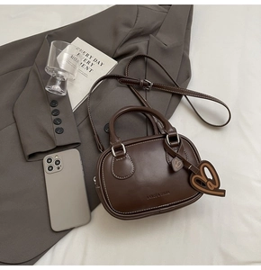 Deep brown matte leather mini bowling bag with heart charm and crossbody strap