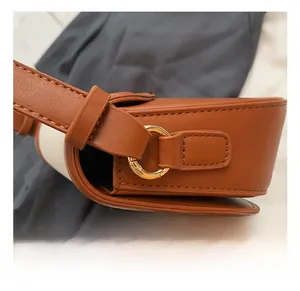 Detailed macro view of the gold-tone metal ring hardware and fine stitching on a brown bag