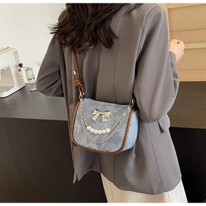 Detail of light blue crossbody bag featuring a silver bow and elegant pearl chain strap