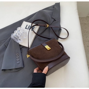 Detail of vintage brown suede bucket bag with leather patchwork and gold metal buckle