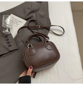 Detail of dark brown mini bowling bag showing contrast white stitching and leather texture