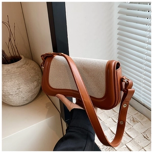 Detail of canvas and brown leather patchwork on the shoulder bag with gold hardware