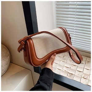 Detailed side view of a vintage beige canvas and brown leather underarm shoulder bag