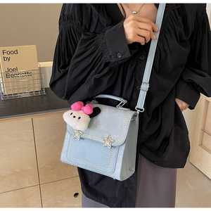 Detail of light blue bag featuring pearl trim, star buckles, and a plush charm detail