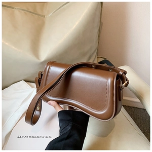 Detail of dark brown leather underarm bag with unique wavy base and gold hardware buckle
