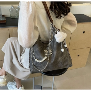 Detail of grey hobo bag with pearl chain decoration and white cloud plush charm